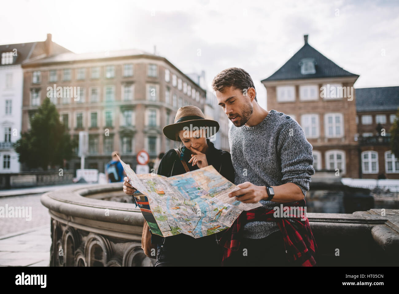 Coppia giovane guardando la mappa di navigazione della città. I turisti di trovare la loro strada guardando una mappa permanente sulla strada. Foto Stock