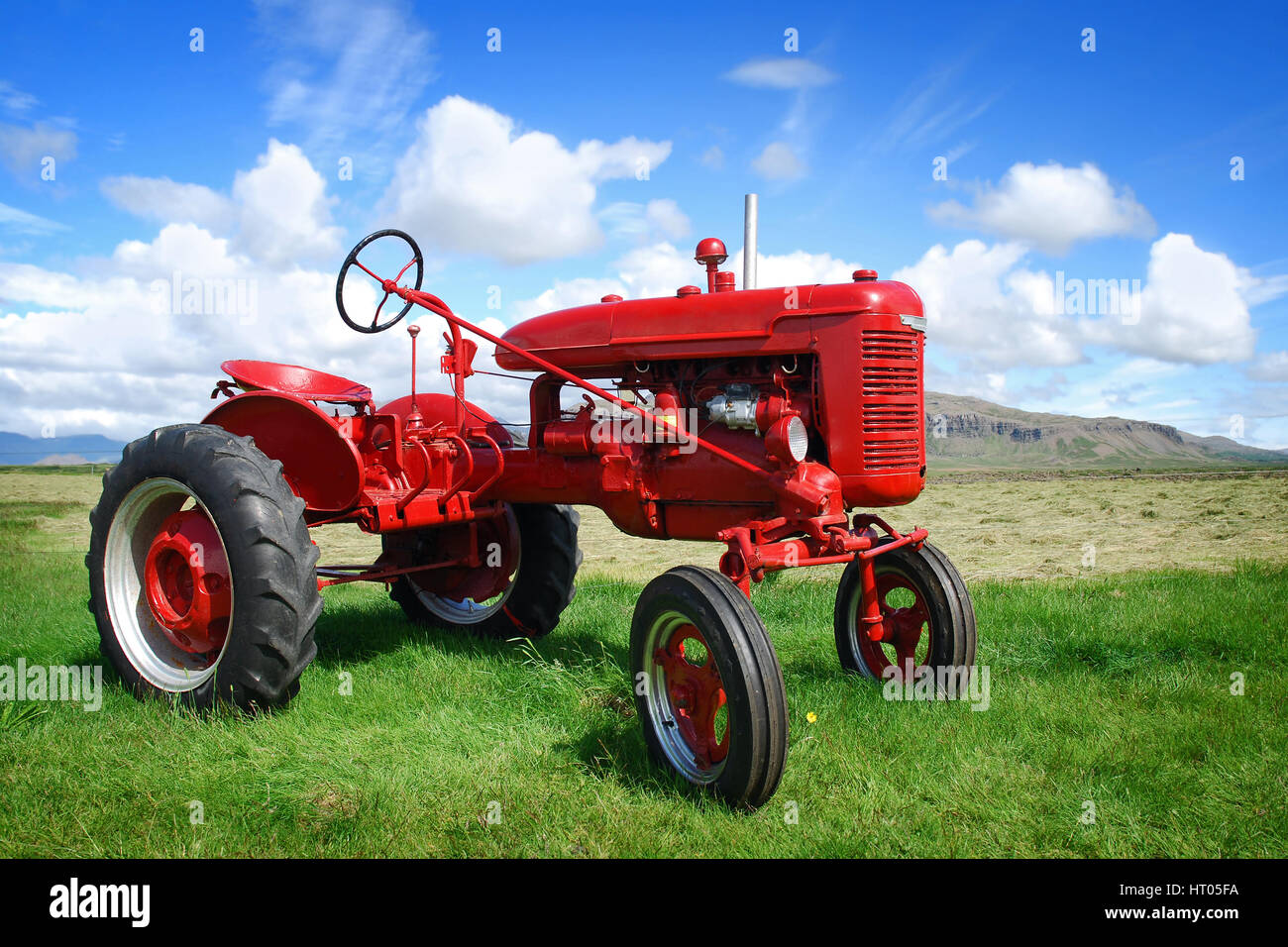Islanda red old school il trattore nel campo verde con bellissimo paesaggio estivo dietro Foto Stock