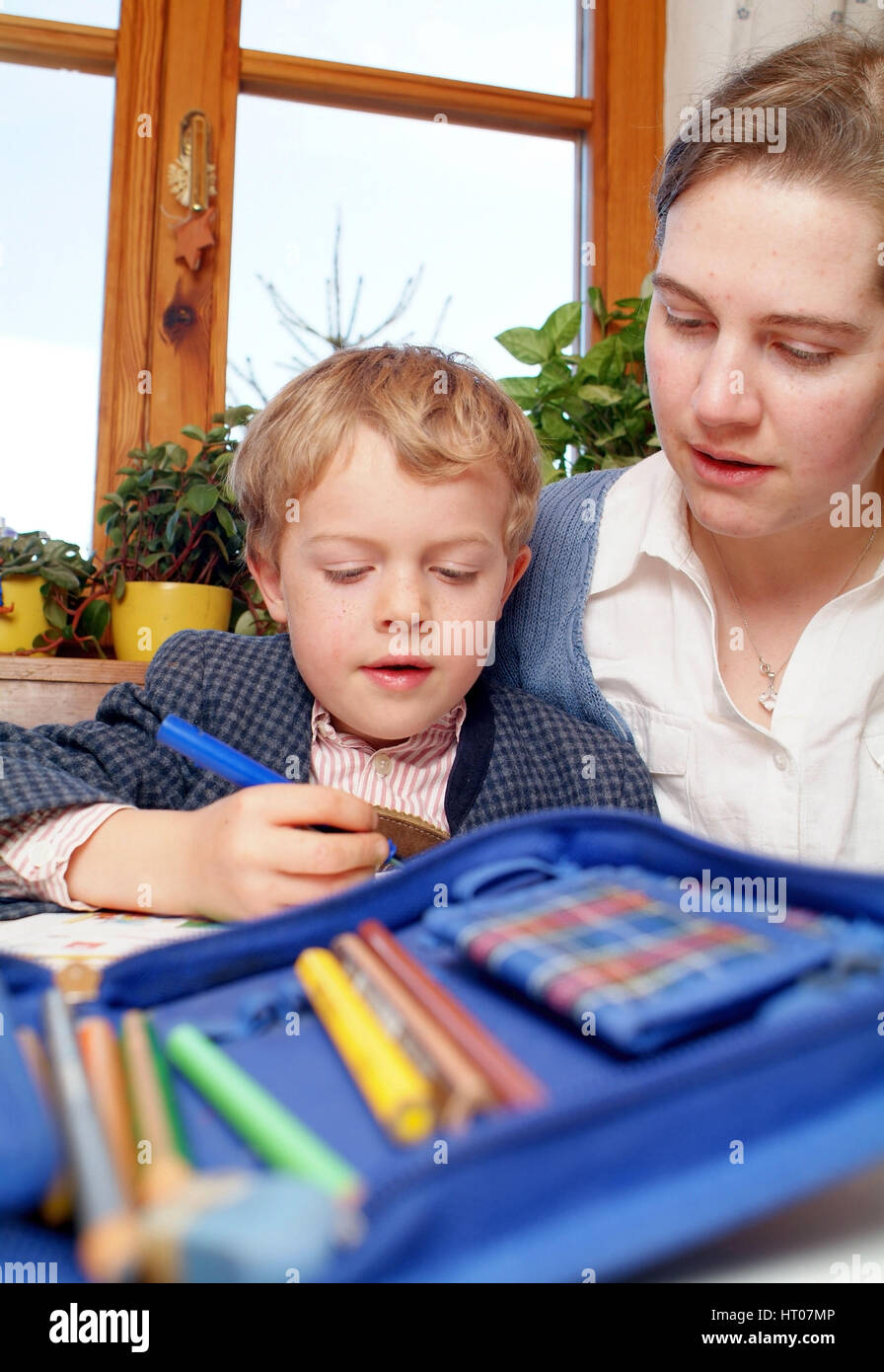 Mutter hilft Schuljungen bei Hausaufgabe - madre contribuisce scolaro con compiti Foto Stock