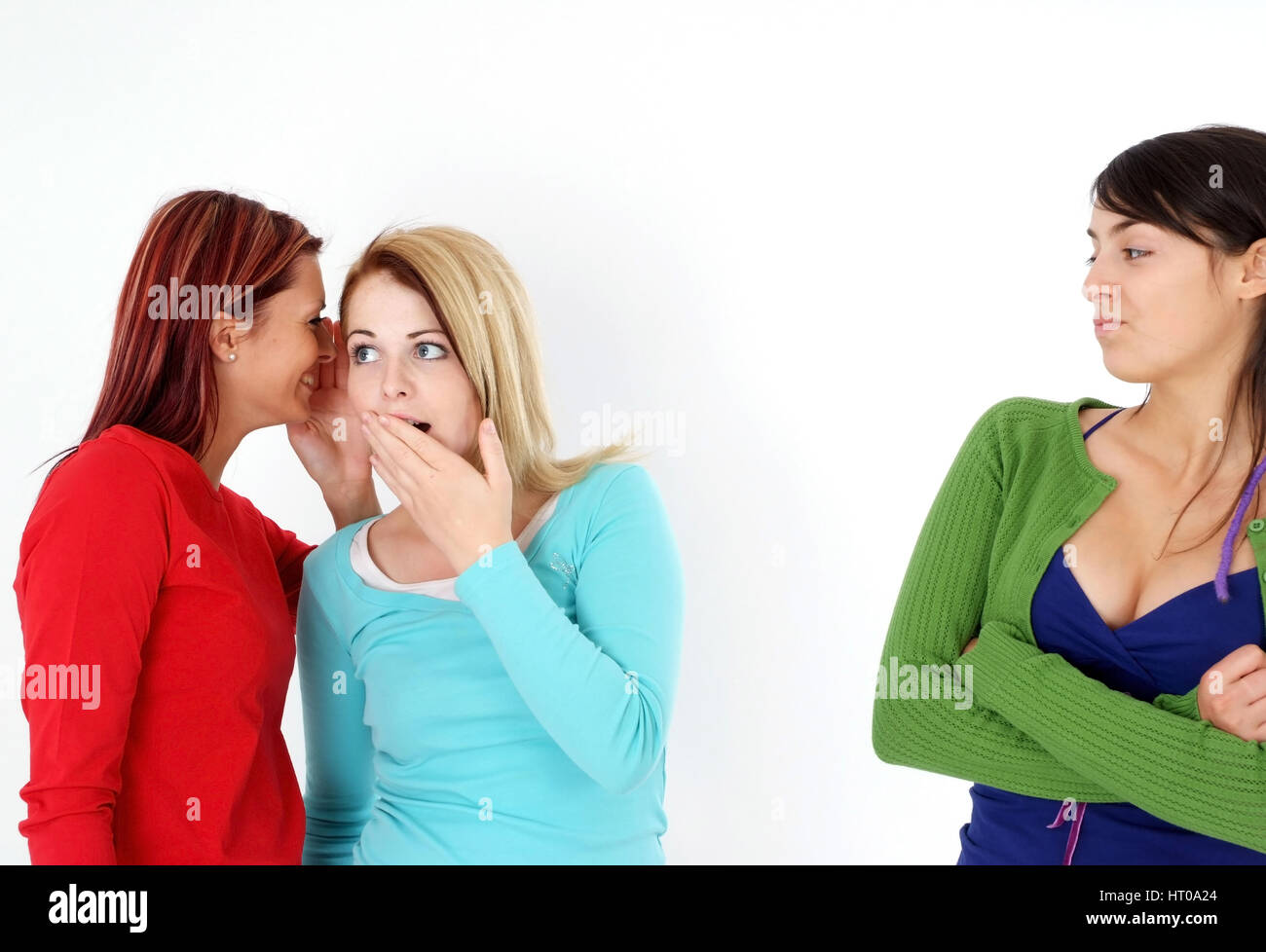 Zwei Frauen fluestern miteinander, eine Frau steht ausgeschlossen daneben - due donne bisbigliano insieme, una donna fuorigioco Foto Stock