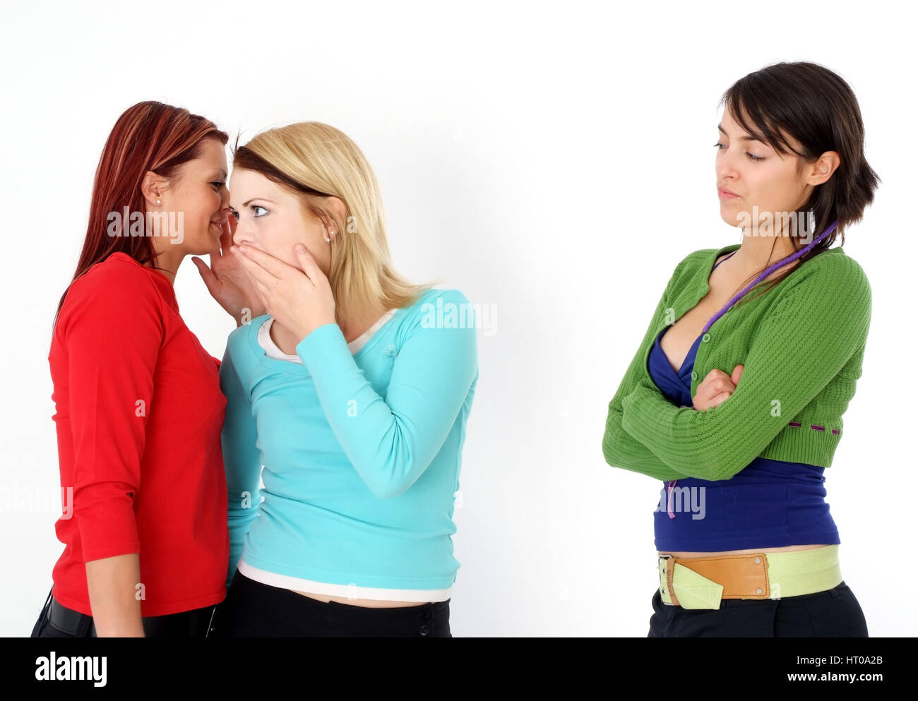 Zwei Frauen fluestern miteinander, eine Frau steht ausgeschlossen daneben - due donne bisbigliano insieme, una donna fuorigioco Foto Stock