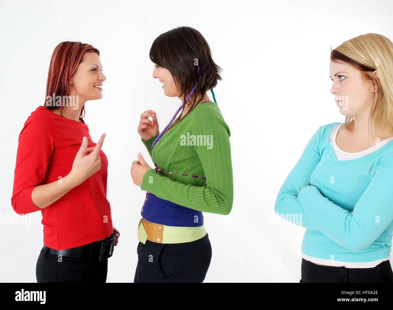 Zwei Frauen tratschen miteinander, eine Frau steht ausgeschlossen daneben - due donne nel parlare, una donna fuorigioco Foto Stock