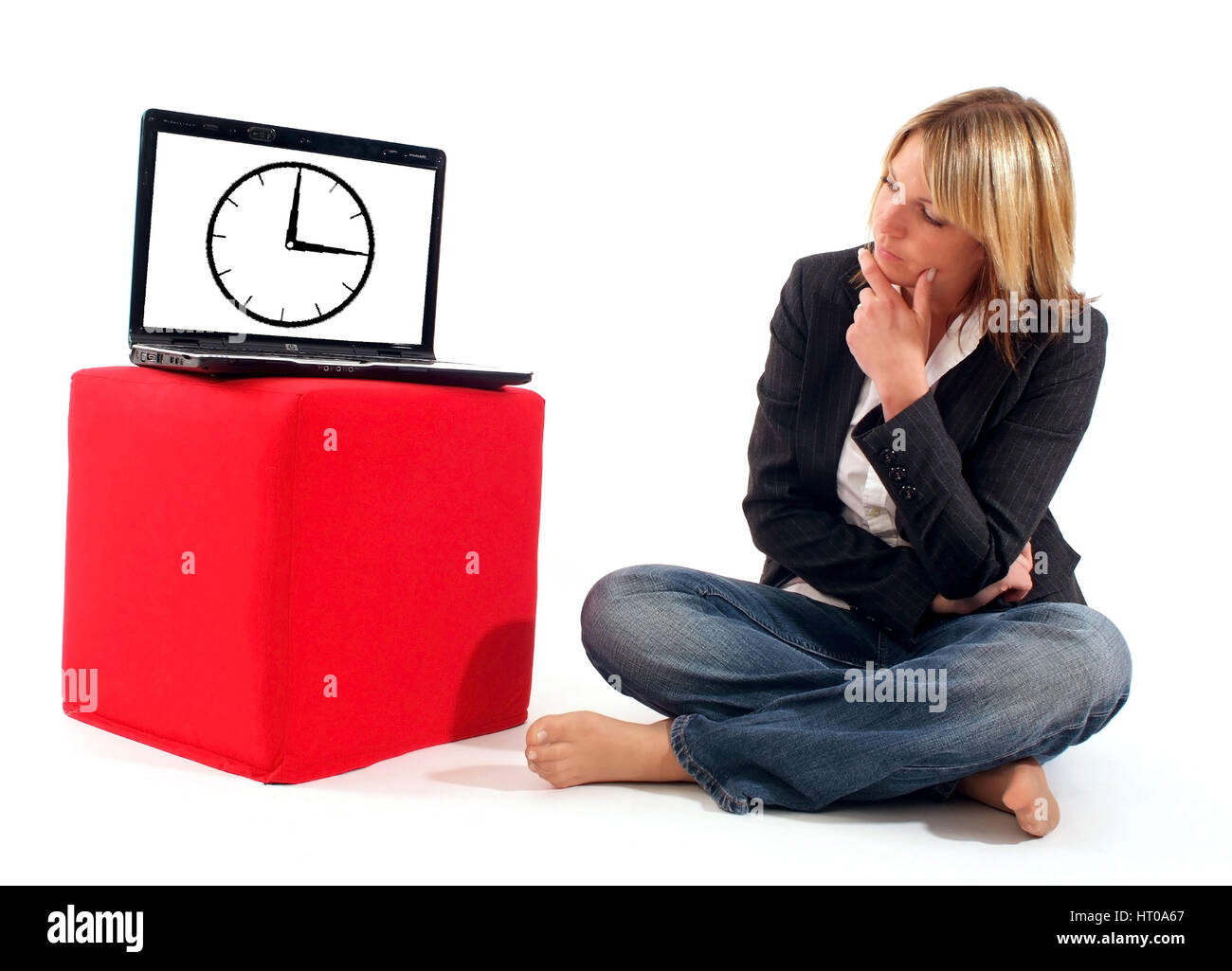 Junge Geschoeaeftsfrau skeptischem mit Blick sitzt neben Laptop mit abgebildeter Uhr am Monitor - young business donna accanto al laptop Foto Stock
