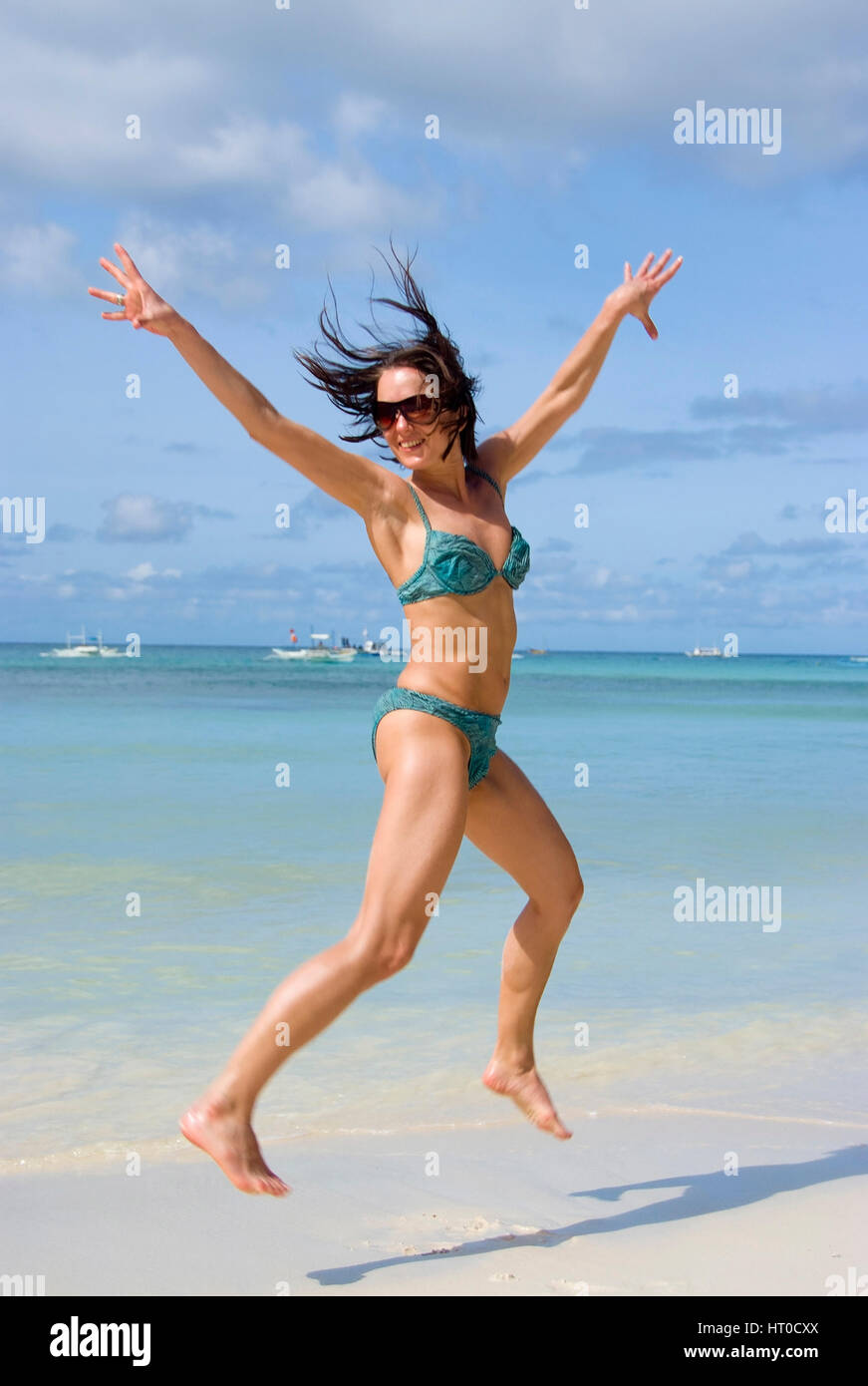 Junge, vitale Frau im springt Bikini am Strand - giovane donna salta sulla spiaggia Foto Stock