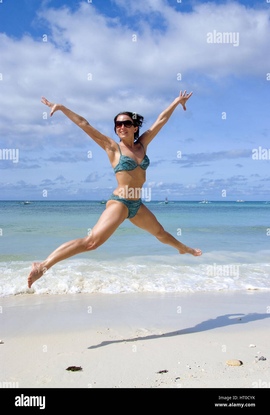 Junge, vitale Frau im springt Bikini am Strand - giovane donna salta sulla spiaggia Foto Stock