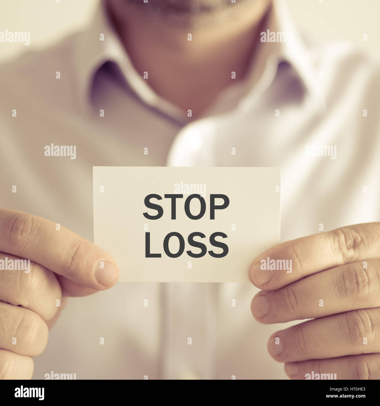 Primo piano su imprenditore tenendo una scheda con il testo stop loss, business Concetto di immagine con soft focus background e tono vintage Foto Stock