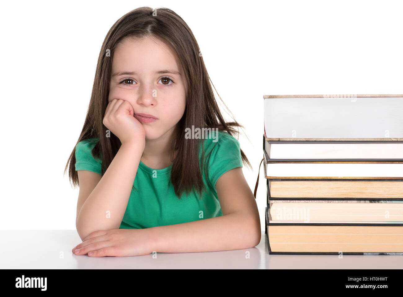 Scuola ragazza seduta dalla pila di libri con grim annoiato faccia. Isolato su uno sfondo bianco. Foto Stock