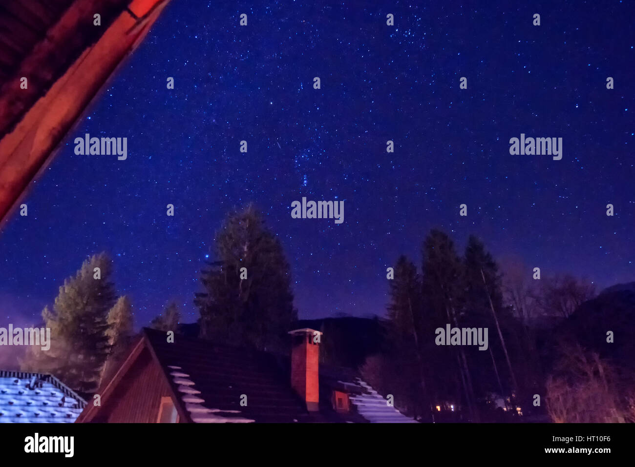 Splendido cielo notturno con stelle su campagna cottage in inverno, una lunga esposizione Foto Stock