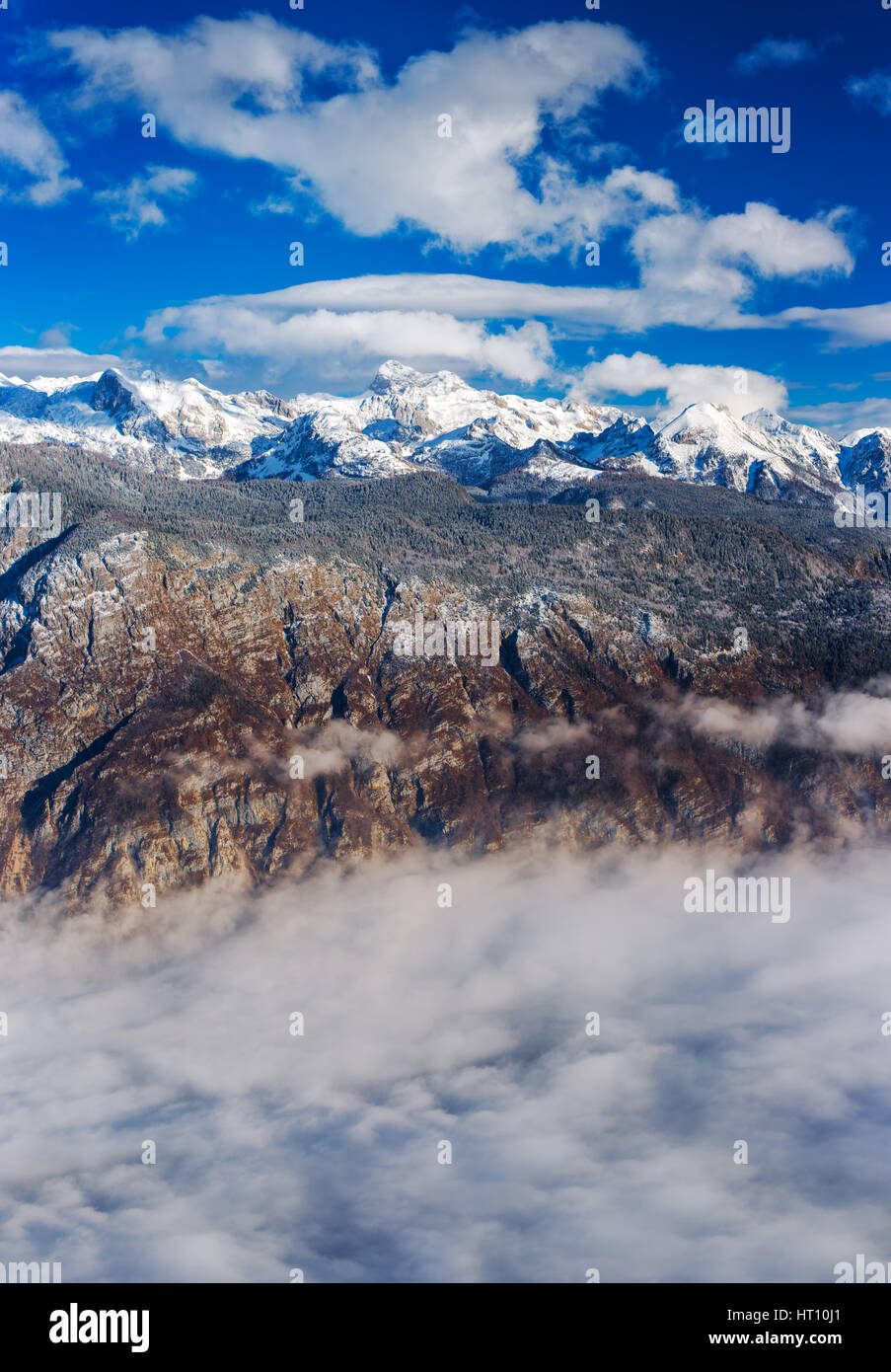 Super resolution impilati paesaggio del monte Triglav top in Slovenia sulla bella e soleggiata giornata invernale con soffici nuvole e nebbia sopra il lago di Bohinj Foto Stock