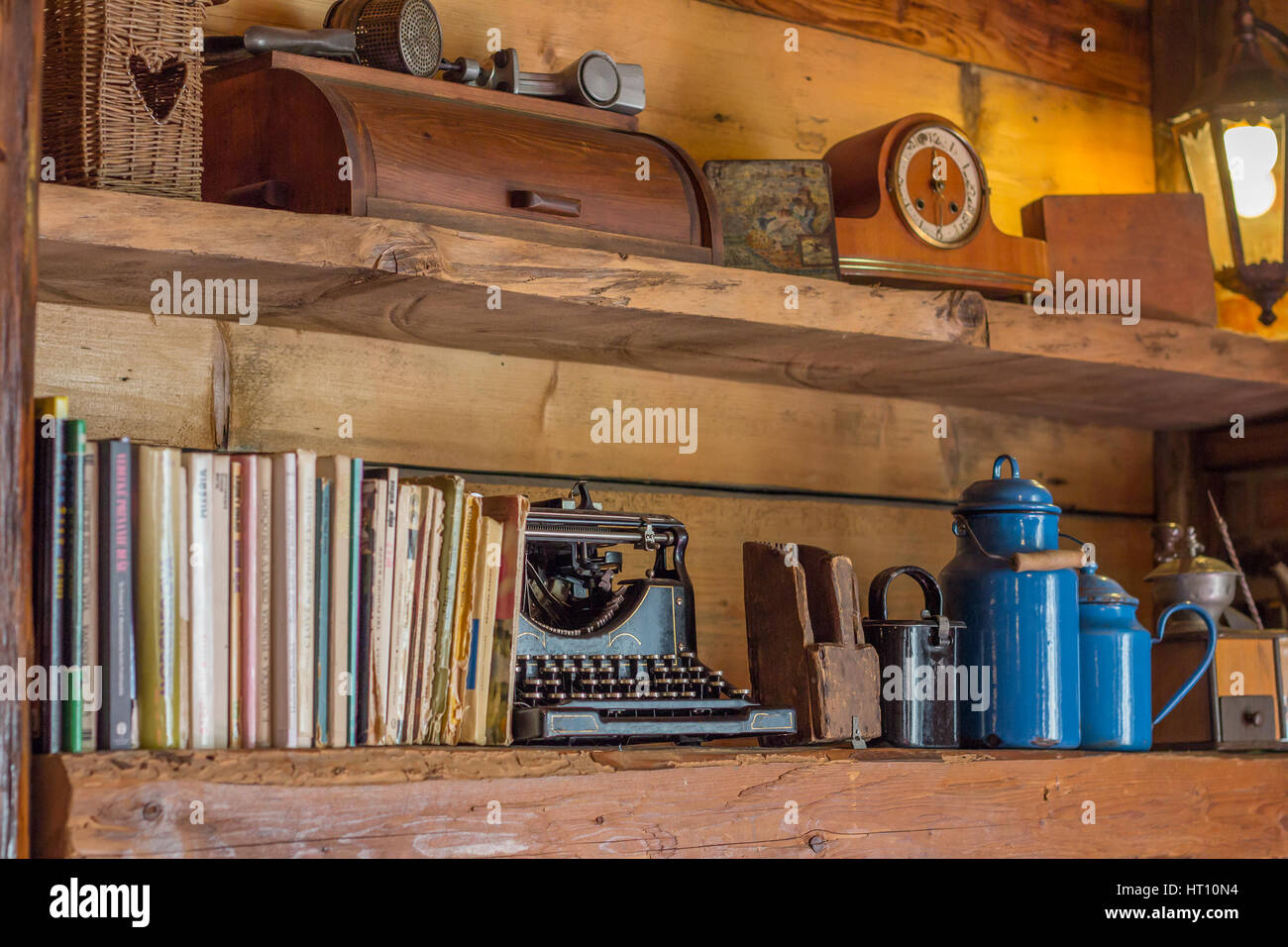 Vista in dettaglio su vecchi scaffali in legno con riviste e antiche macchine da scrivere orologio caraffe e altri oggetti Foto Stock
