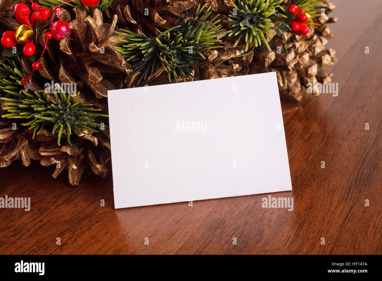 Ghirlanda di Natale con rosso e oro decorazioni ninnolo, prua, agrifoglio, vischio, pigne, abeti e blanck scheda Sfondo di legno, posto per te Foto Stock