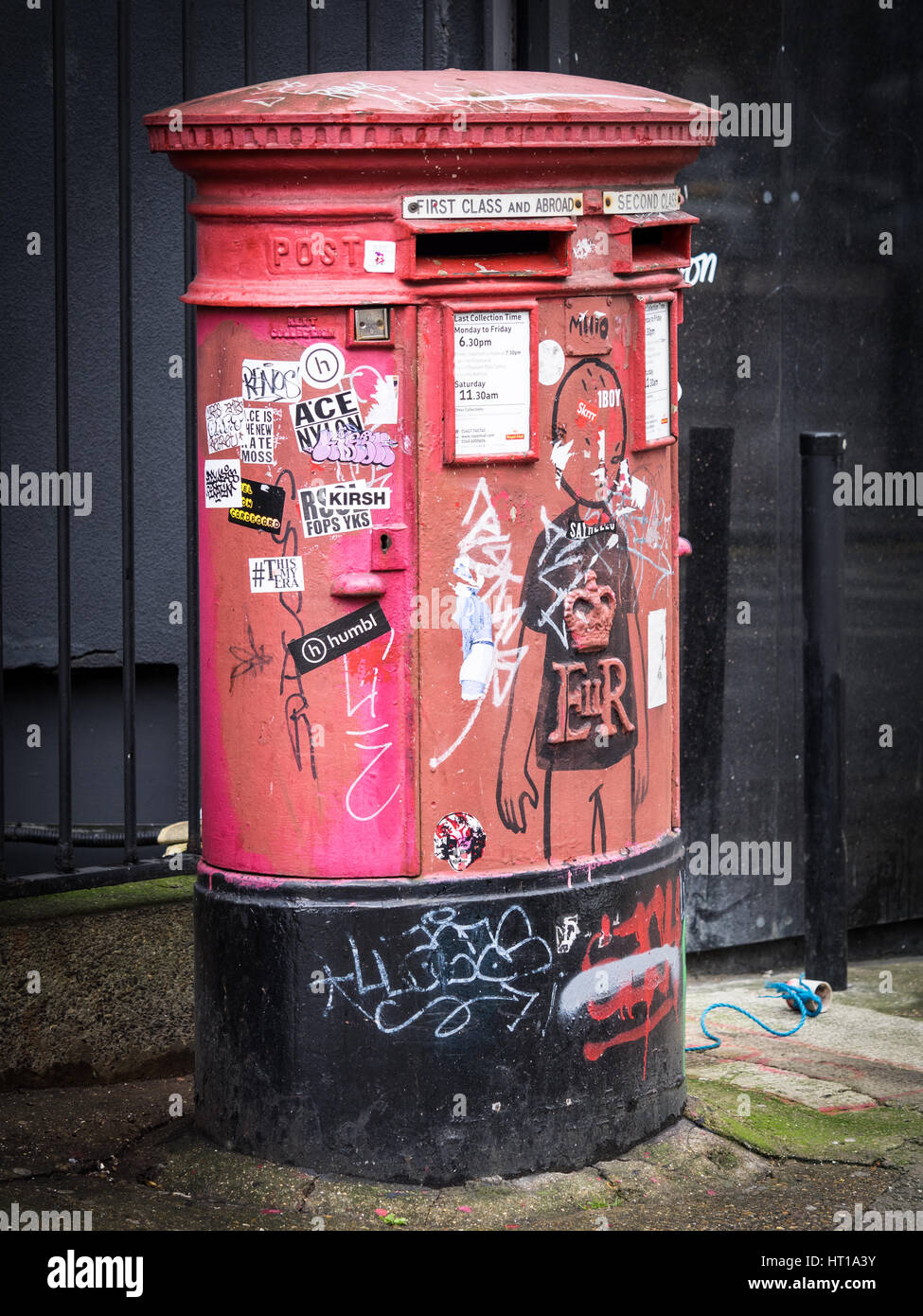 Un grafitti e adesivo decorato Royal Mail casella postale a Londra alla moda di area di Shoreditch Foto Stock