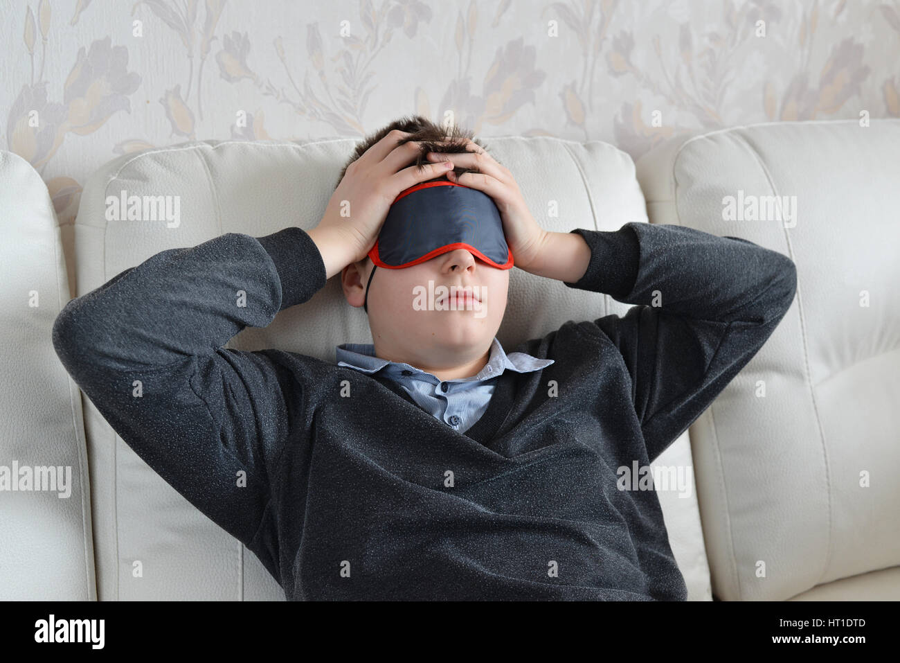 Un adolescente con un mal di testa in maschera per dormire Foto Stock