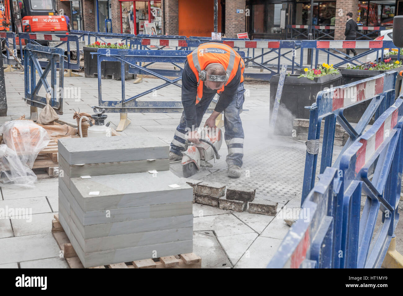 Un operaio del consiglio utilizzando un utensile elettrico per tagliare il blocco, pavimentazione in Durham city,l'Inghilterra,UK Foto Stock