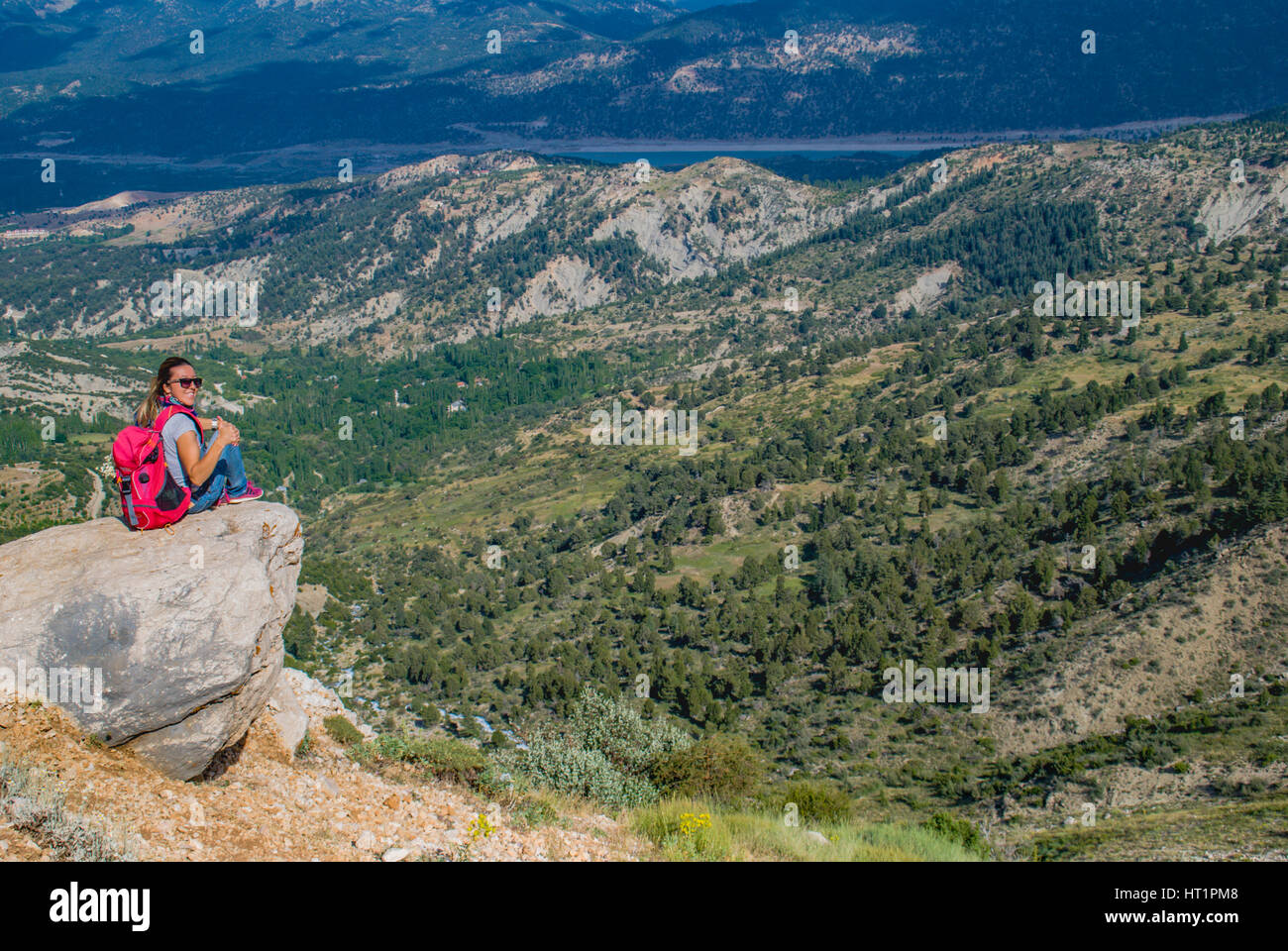 Donna seduta sulla roccia cercando di la valle Foto Stock