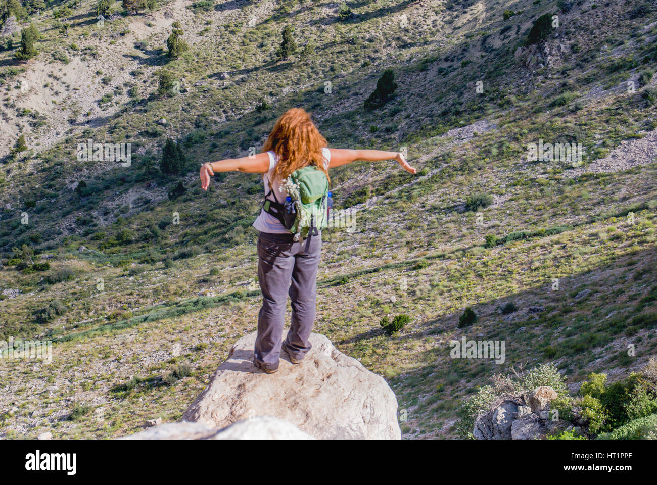 La ragazza di natura permanente sulla roccia bracci aperti a guardare la valle sottostante Foto Stock