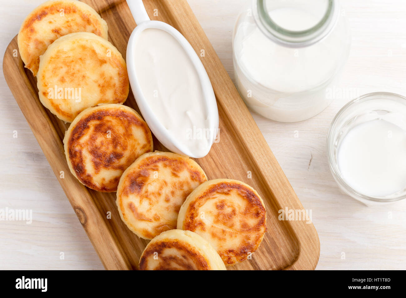 In casa cottage cheese pancakes su bianco tavolo in legno servito con panna acida. Syrniki, tradizionale cucina ucraino Foto Stock