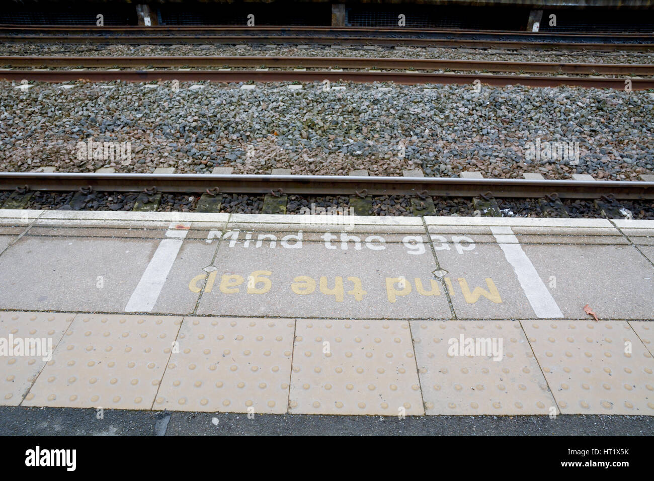 Dipinto si prega di mente il divario segno sulla stazione ferroviaria platform Foto Stock