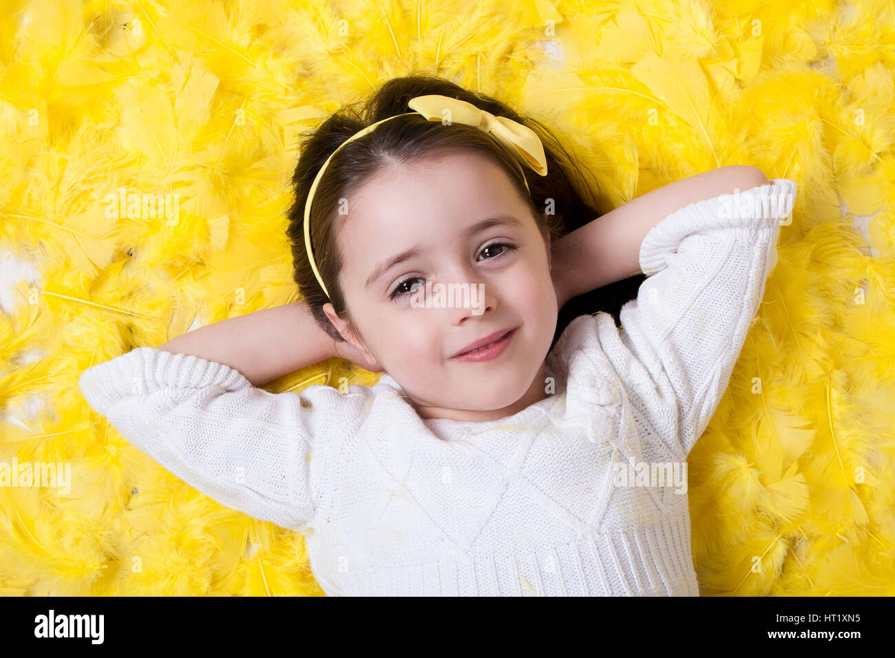 Felice fiducioso ragazza posa su una piuma gialla - Primavera/Pasqua prop Foto Stock
