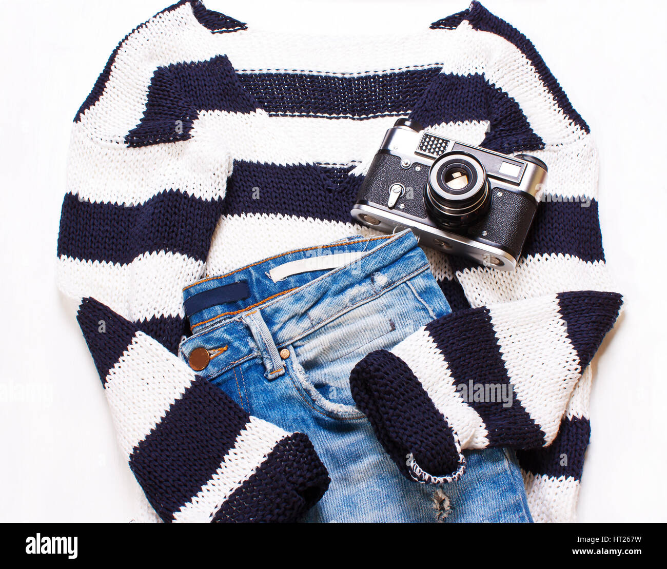 Abbigliamento donna, maglione, jeans e una telecamera su uno sfondo bianco. Il concetto di moda donna elegante. Vista superiore, piatto Foto Stock