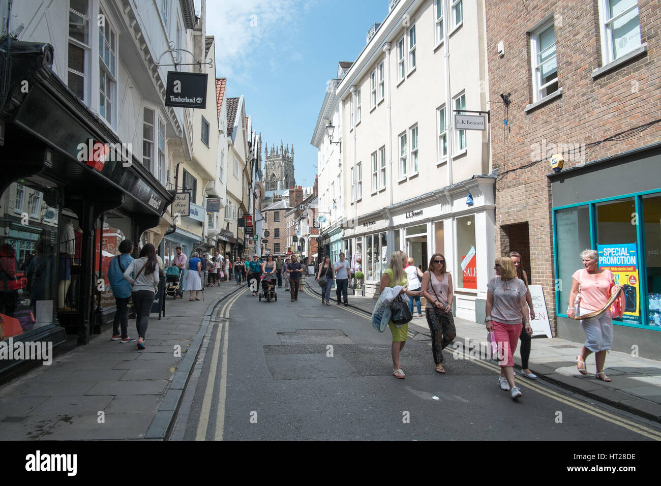 Gli acquirenti e i turisti godono di un inglese estate del giorno su Low Petergate, York, North Yorkshire, Regno Unito. Foto Stock