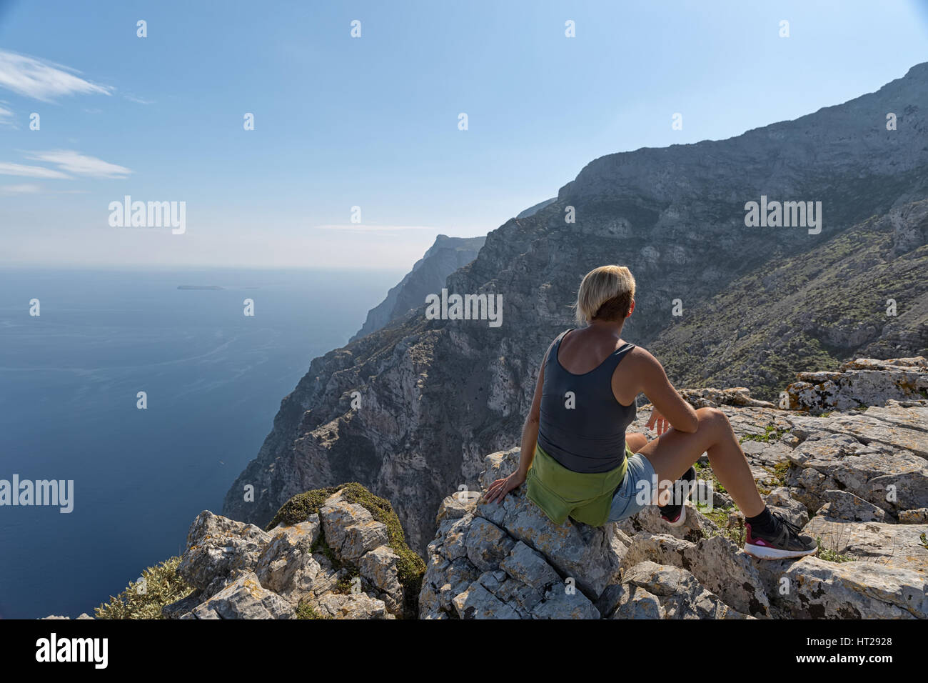 Donna seduta sulle rocce di ammirare un bellissimo paesaggio marino della vista del mare e spiaggia rocciosa, il Mare Egeo, Amorgos Island, Grecia Foto Stock