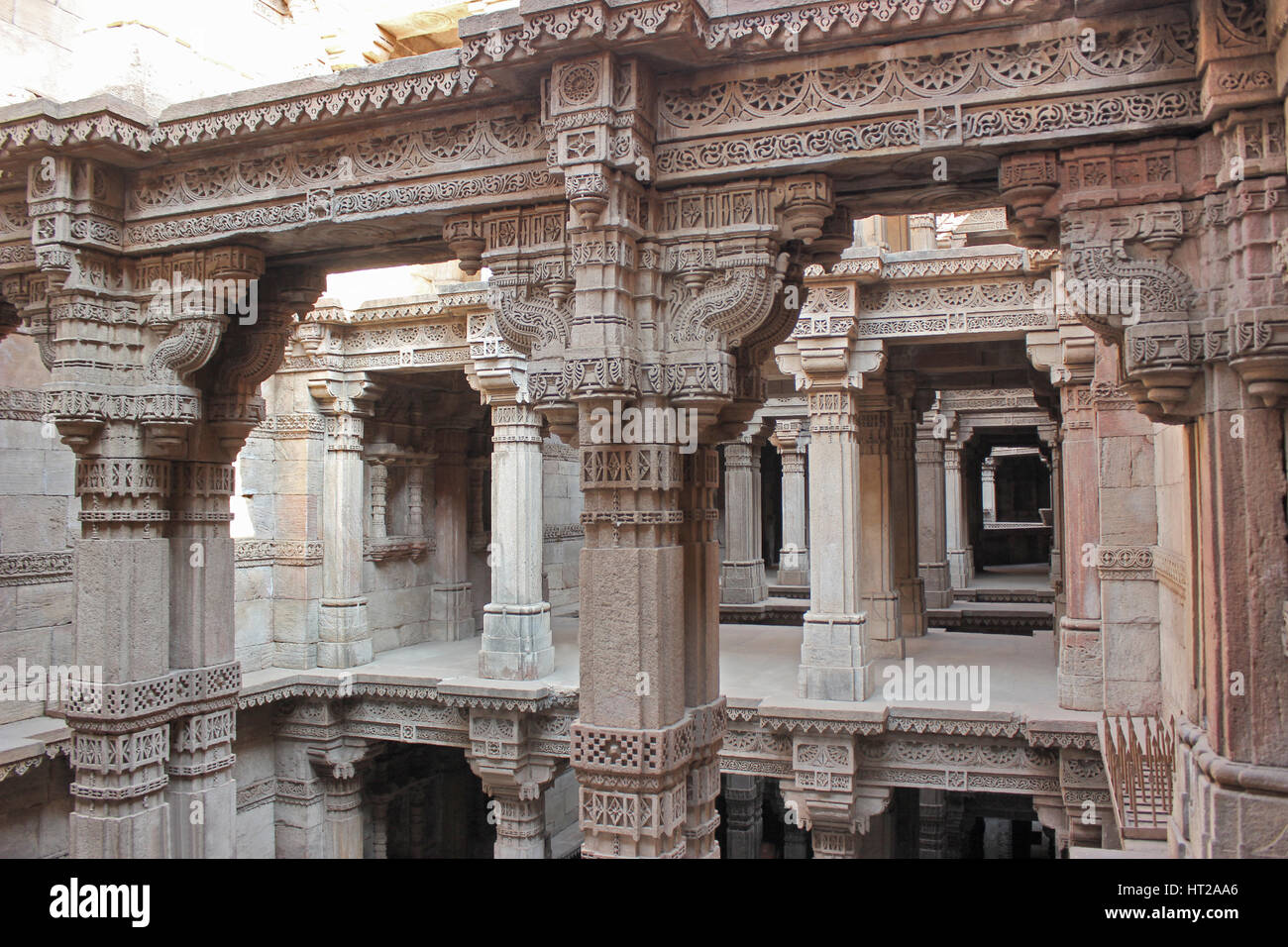 Piani superiori con intricati intarsi in pietra su pilastri, lesena e trabeazione. Adalaj Stepwell, Ahmedabad, Gujarat, India. Foto Stock