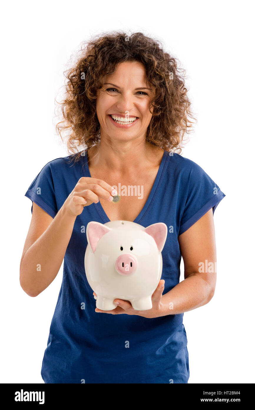Ritratto di un felice donna di mezza età messa un po' di soldi su un Piggybank Foto Stock