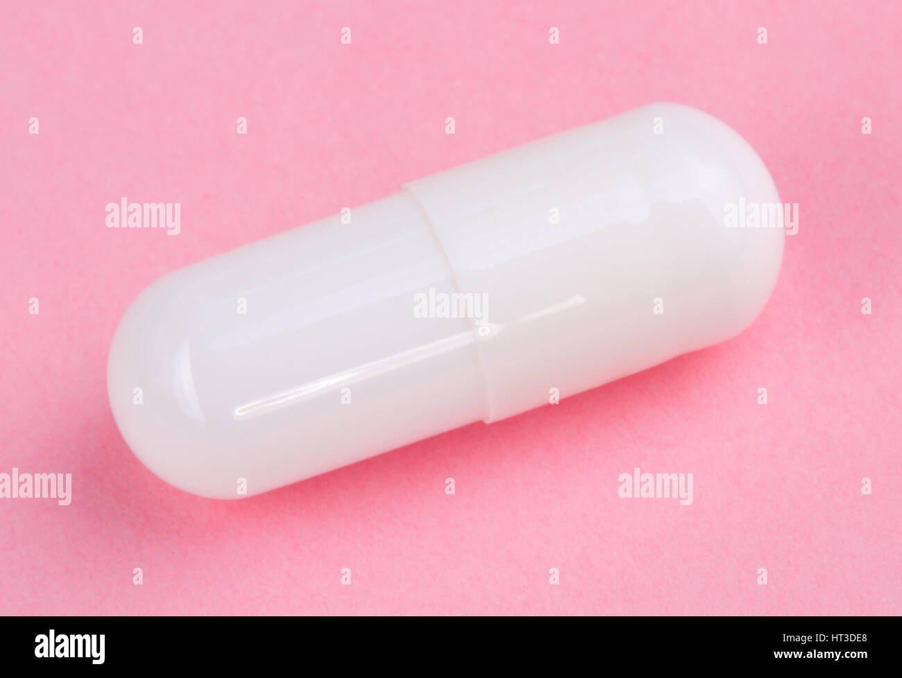 Pillola bianco su sfondo rosa Foto Stock