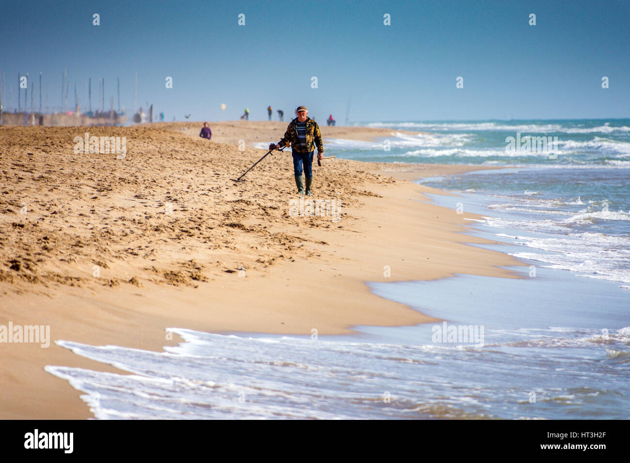 L'uomo con il rivelatore di metalli sulla spiaggia Foto Stock