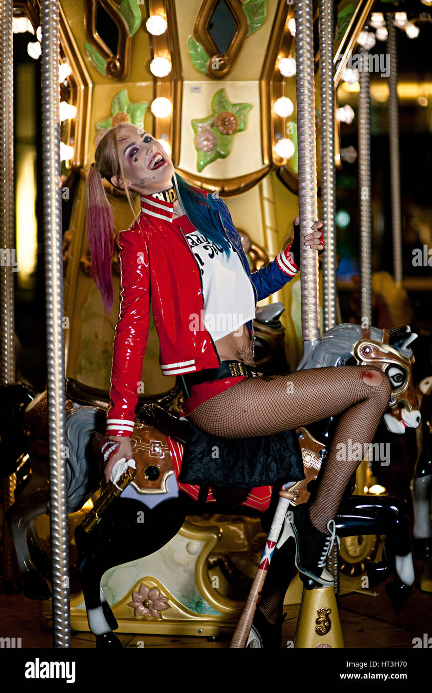 Cosplayer sorridente ragazza in costume Harley Quinn sulle luci di sfondo  della giostra in corsa. Cosplay Foto stock - Alamy
