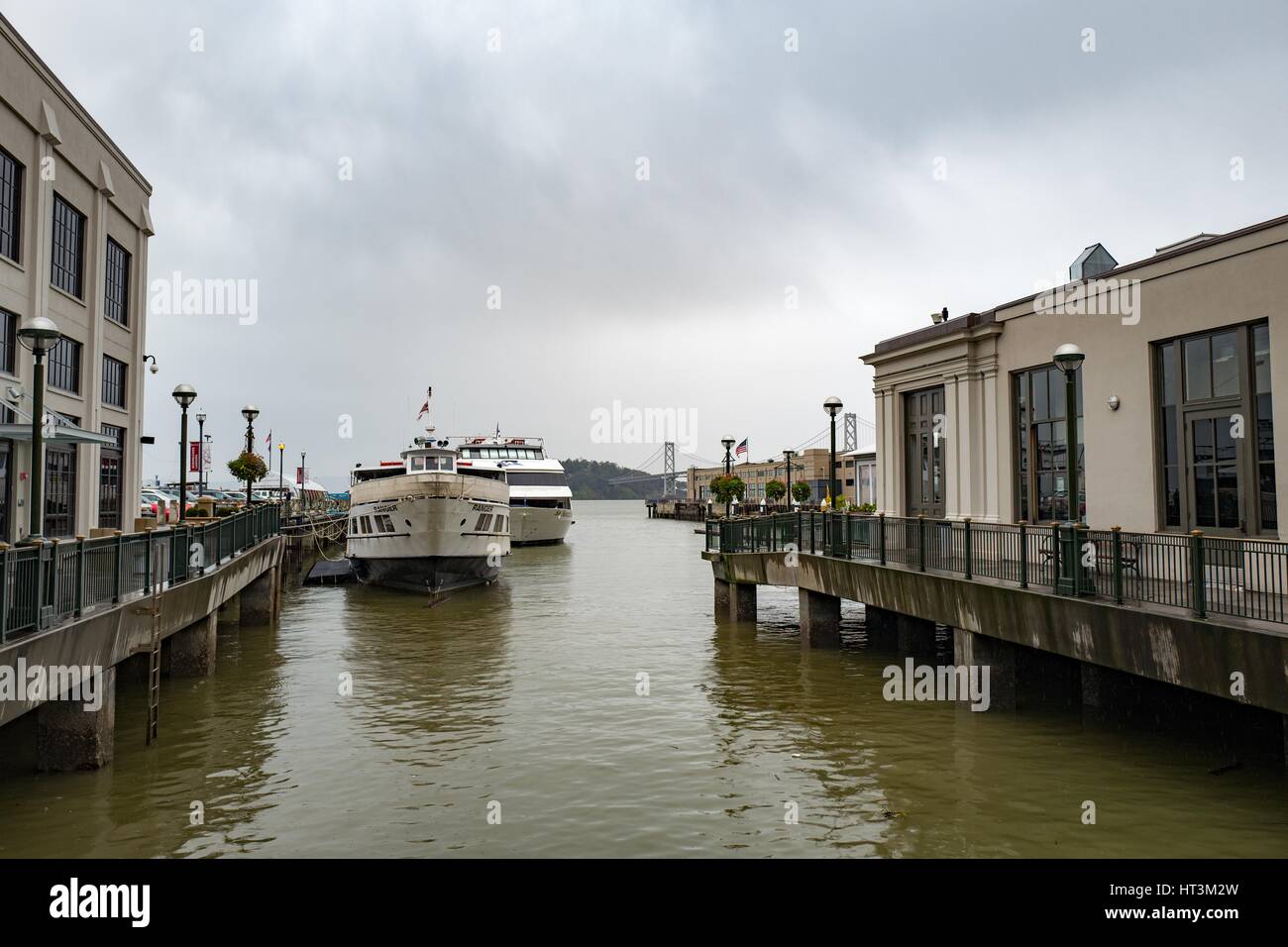Traghetti lungo un molo al Embarcadero, con il Bay Bridge visibile in distanza, San Francisco, California, 22 gennaio 2017. Foto Stock