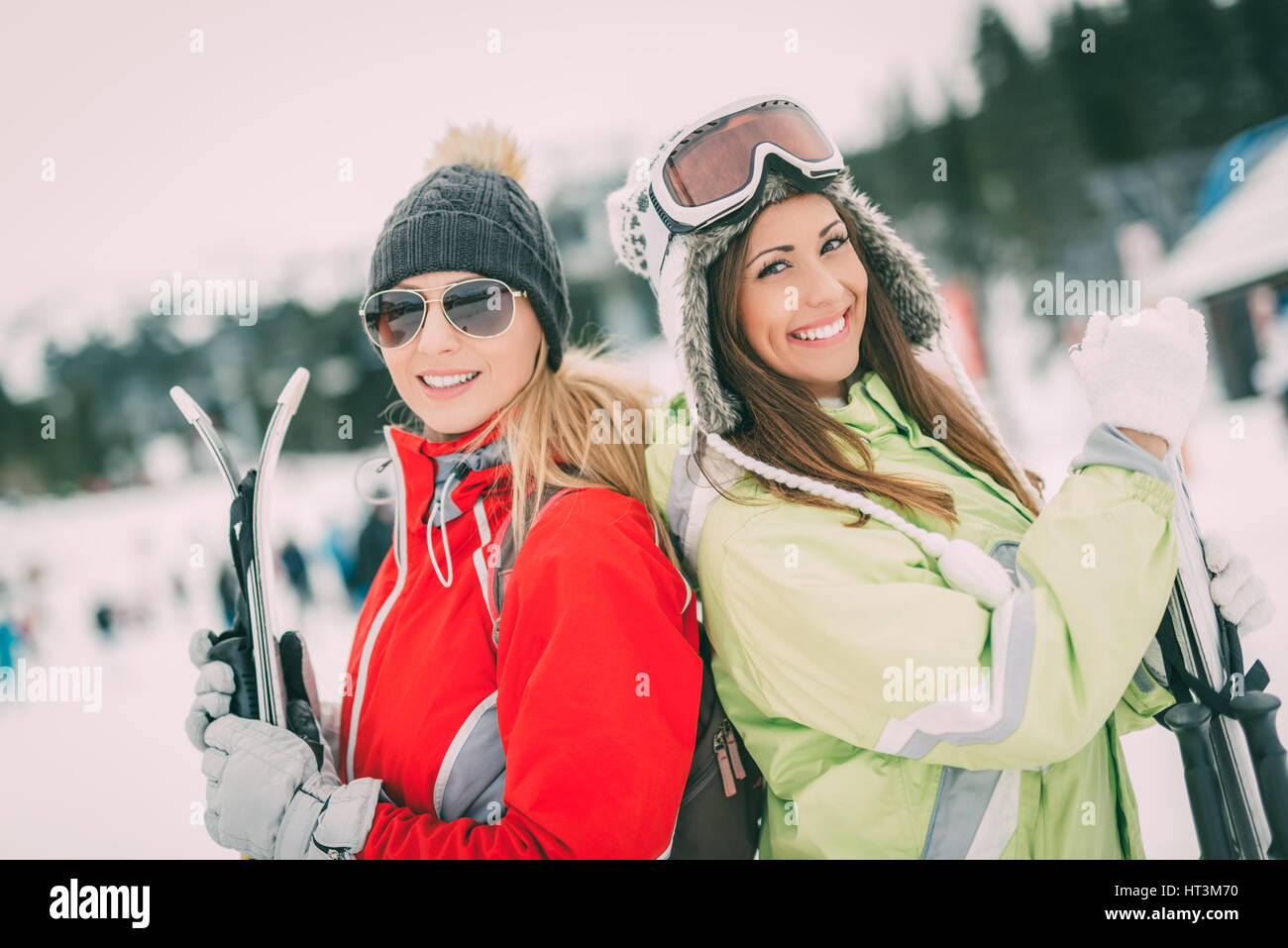 Bella giovane donna amici godendo di una vacanza invernale. Essi in piedi con gli sci e guardando la fotocamera con sorriso. Foto Stock