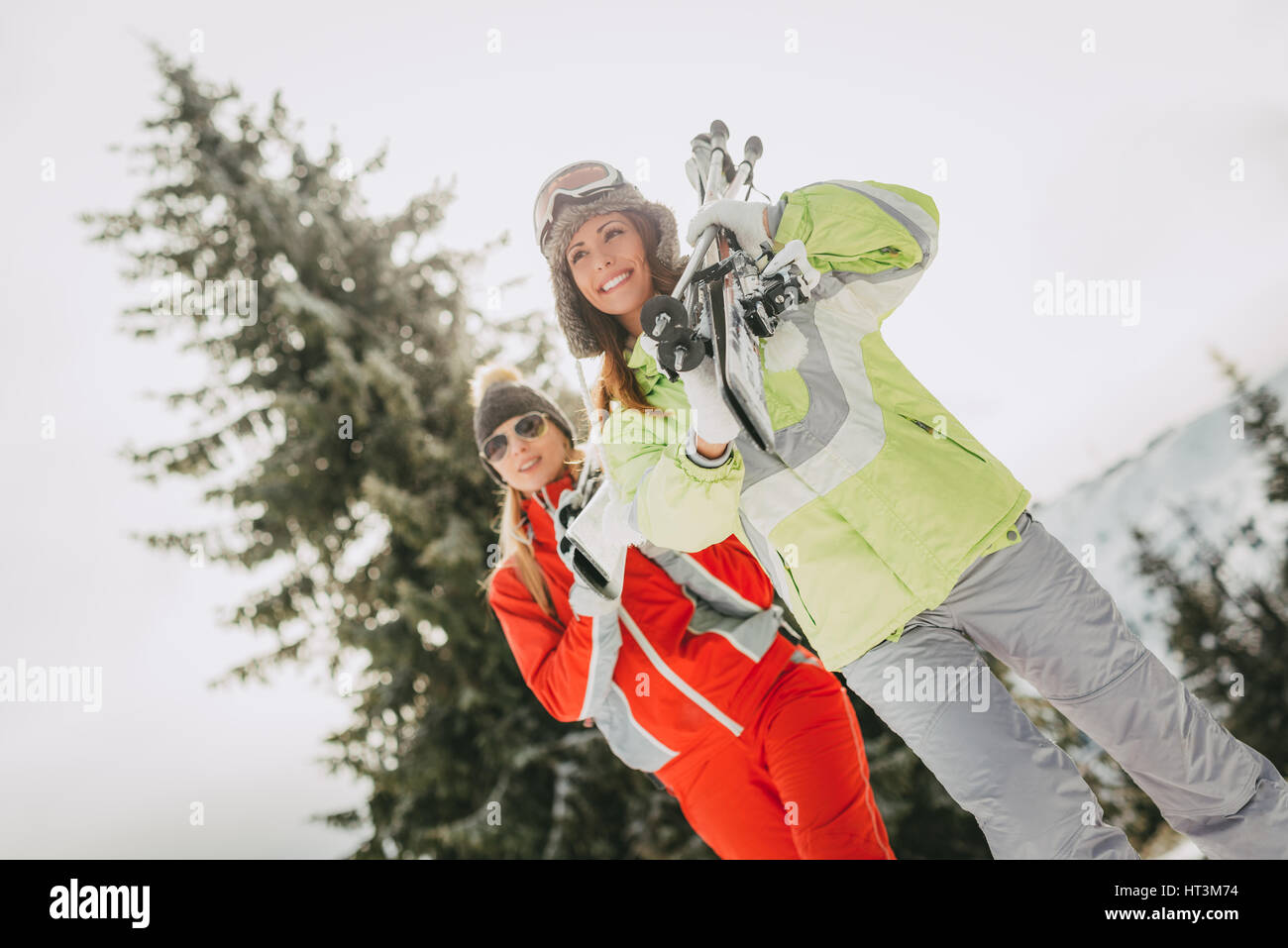 Bella giovane donna amici godendo di una vacanza invernale. Essi in piedi con gli sci e guardando lontano con il sorriso. Foto Stock