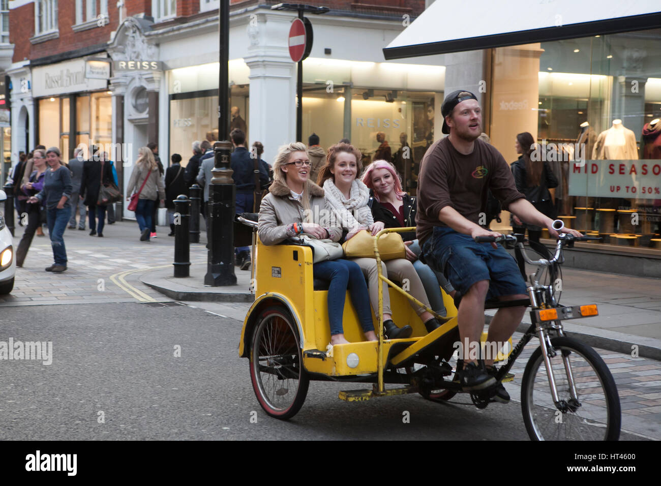 LONDON, Regno Unito - 16 MARZO 2016: un uomo a cavallo di un rickshaw con felici donne nella schiena giù per una strada di Londra Foto Stock