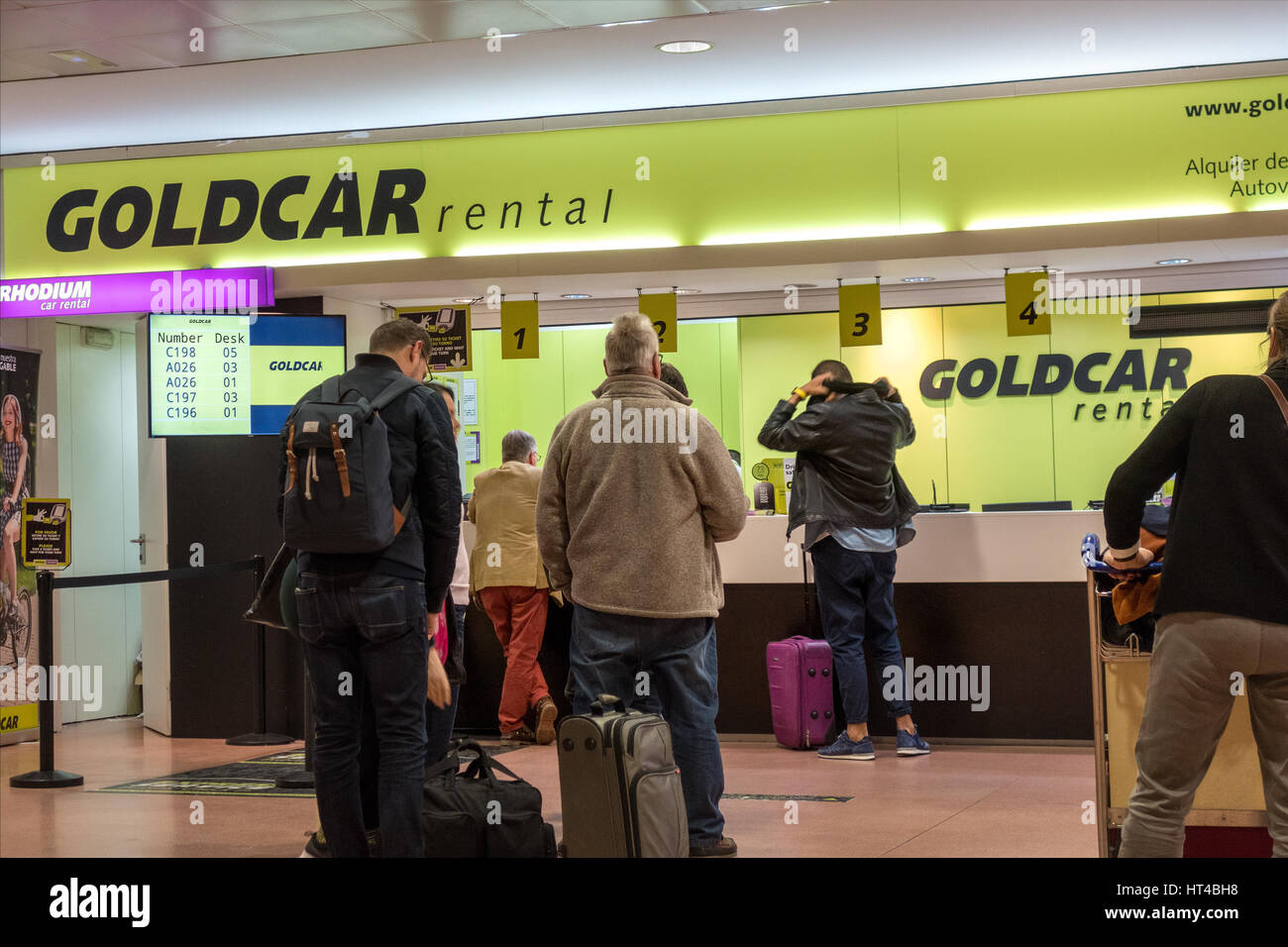 Goldcar oro noleggio auto noleggio auto noleggio desk presso l'aeroporto di Malaga con clienti in linea. Foto Stock