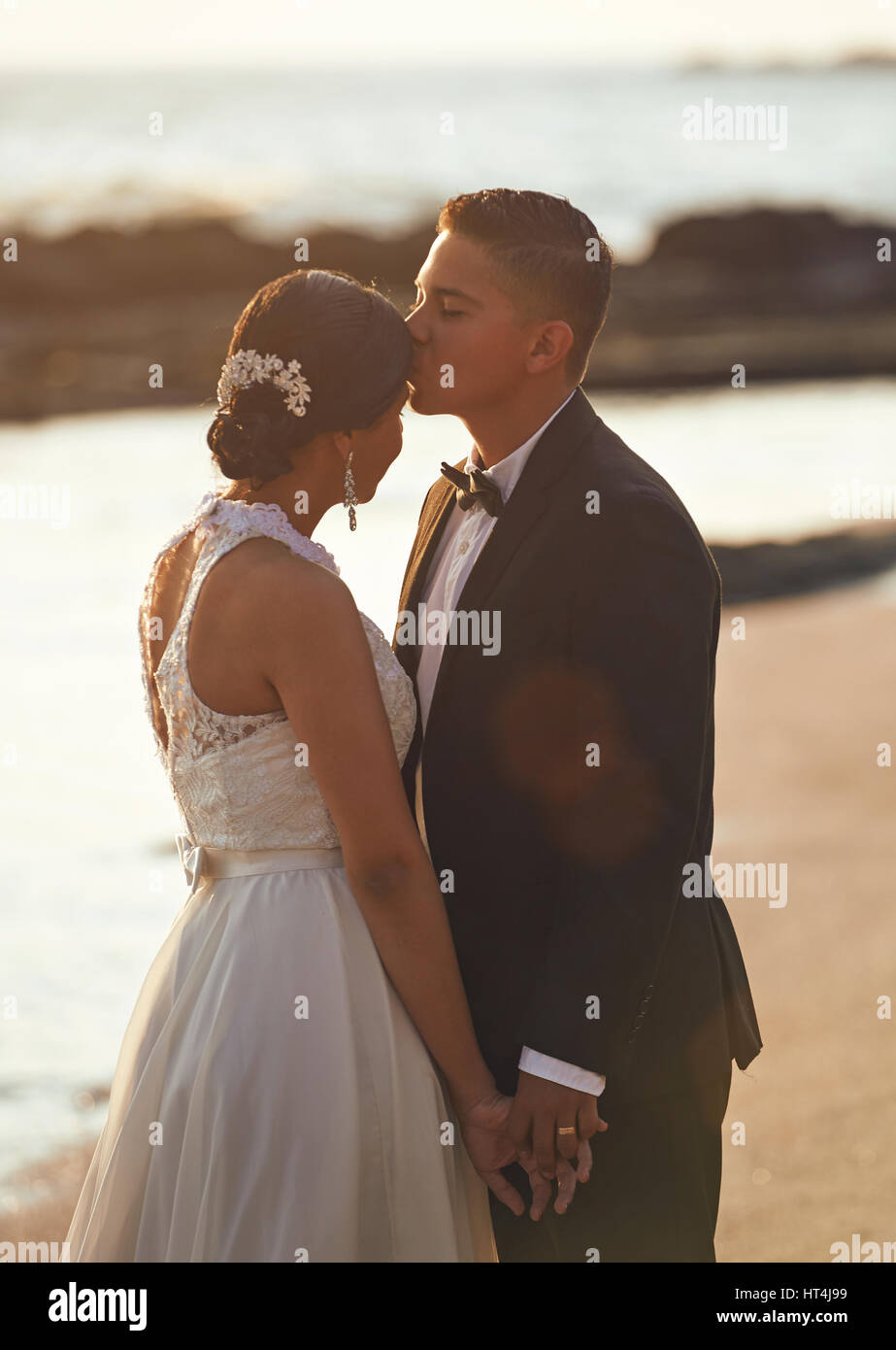 Il bacio sposato coppie in viaggio di nozze di sunny beach sunset. Serata romantica per la coppia giovane Foto Stock