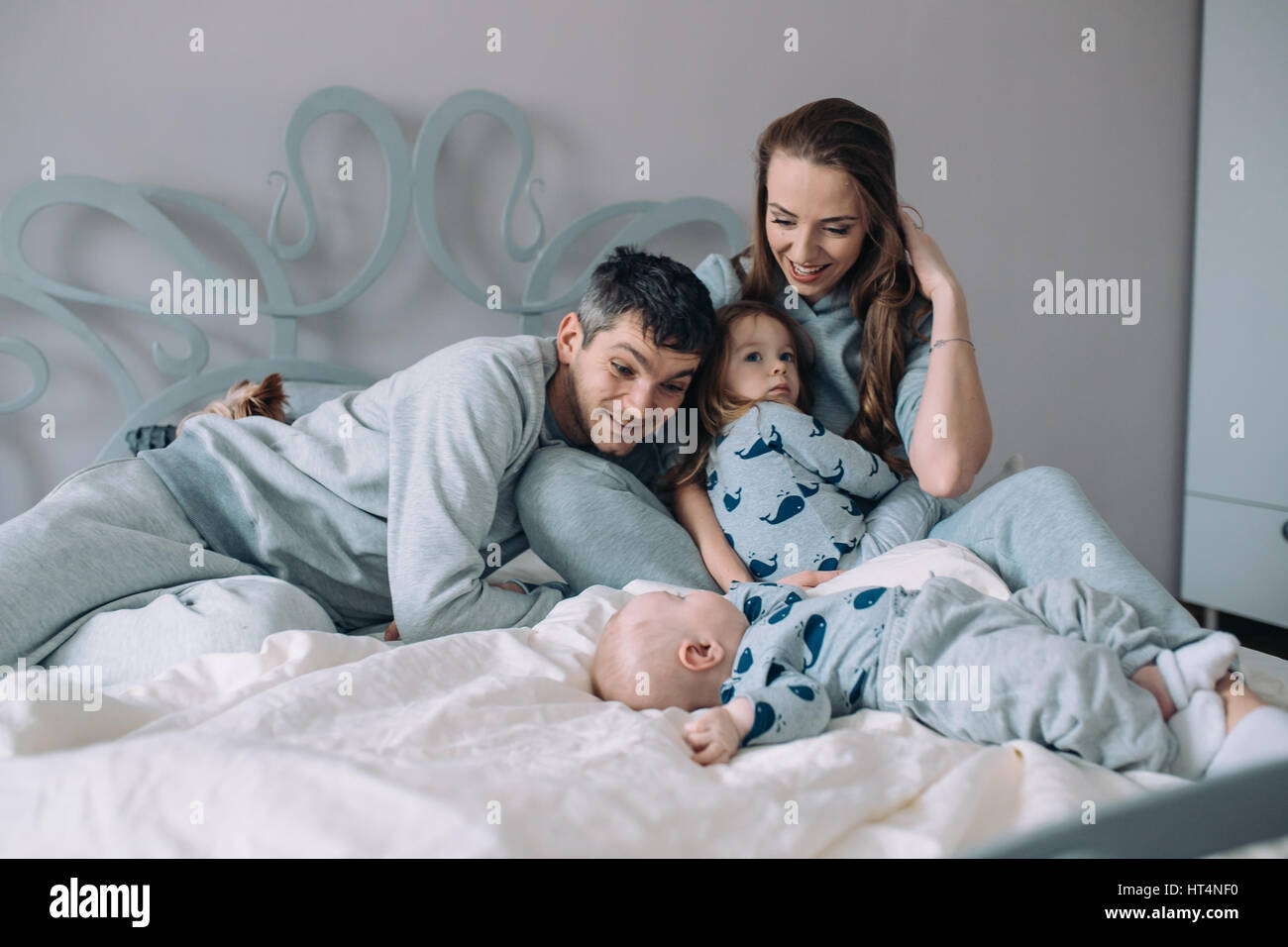 La famiglia felice - madre, padre e figlia e baby sul letto Foto Stock