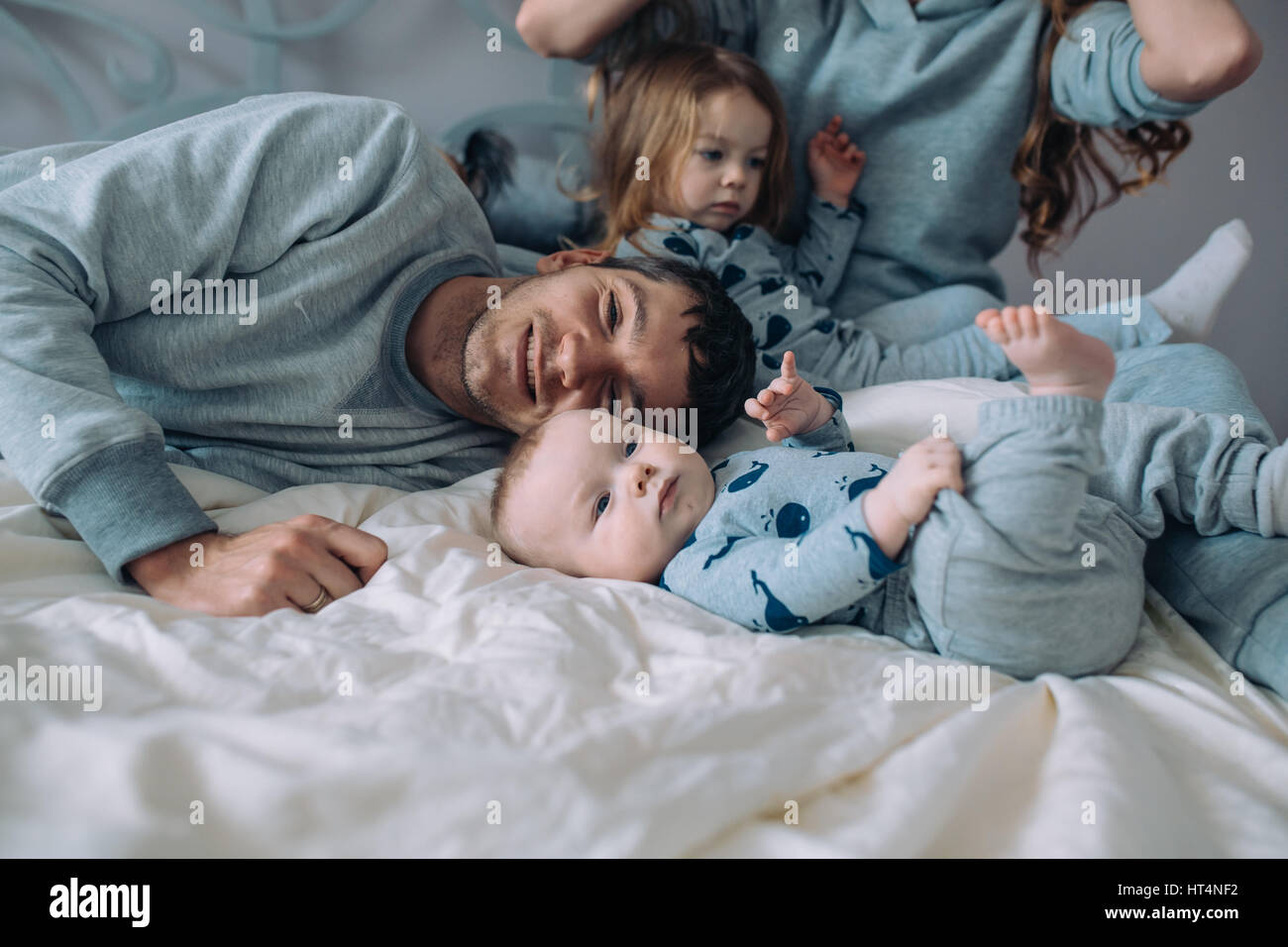 La famiglia felice - madre, padre e figlia e baby sul letto Foto Stock