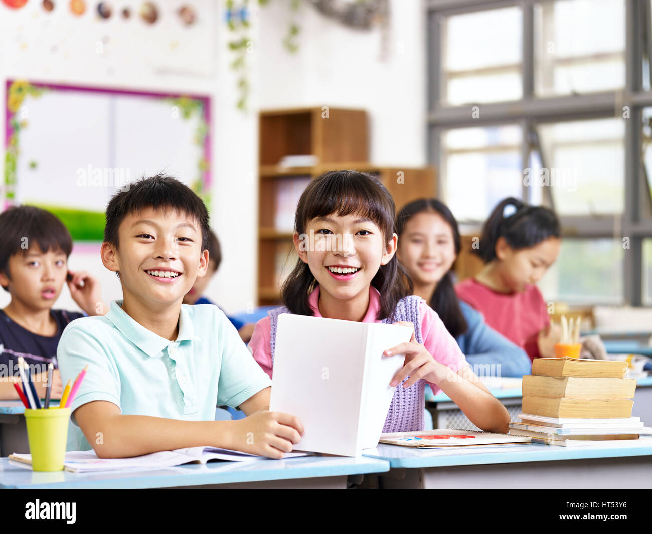 Ritratto di asian gli studenti della scuola elementare in aula guardando la telecamera sorridendo. Foto Stock