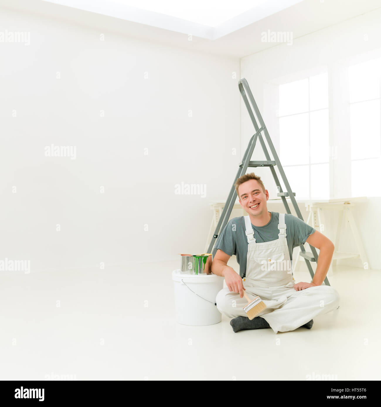 Square ritratto di uomini nella sua luminosa casa bianca. riparare, la costruzione e la ristrutturazione e il concetto di persone Foto Stock