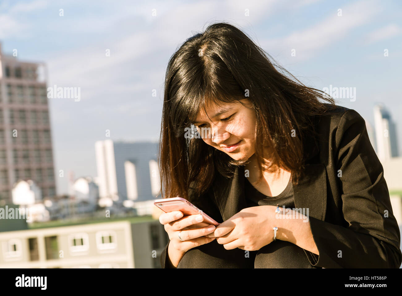 Dirigenti che lavorano con un telefono cellulare sul tetto degli edifici per uffici in background Foto Stock