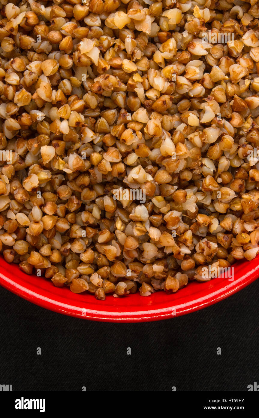 La dieta alimentare - Calda Cereali di grano saraceno in una ciotola di colore rosso su sfondo nero Foto Stock