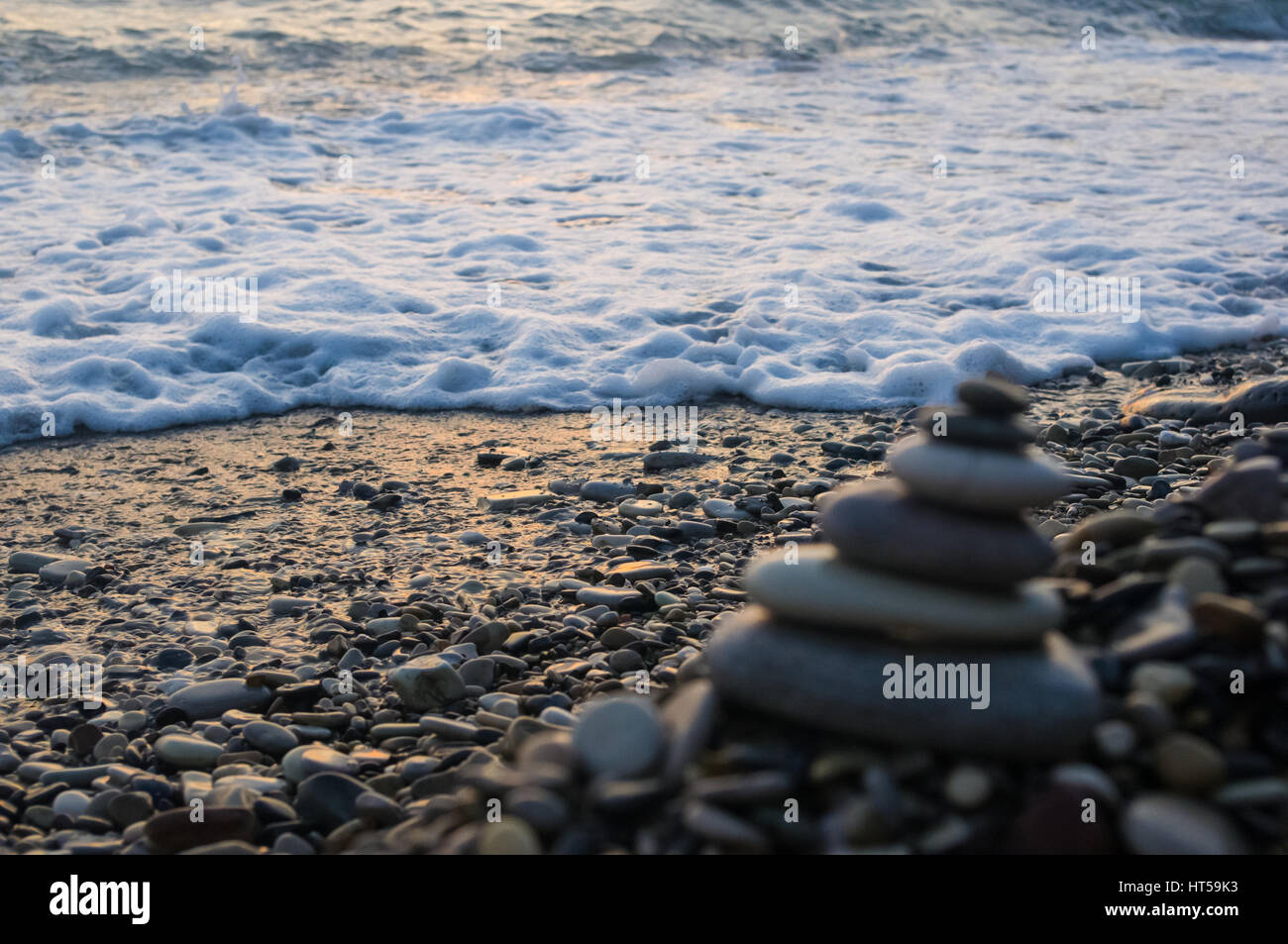 Piramide piegata Zen pietre ghiaia sul mare spiaggia al tramonto Foto Stock