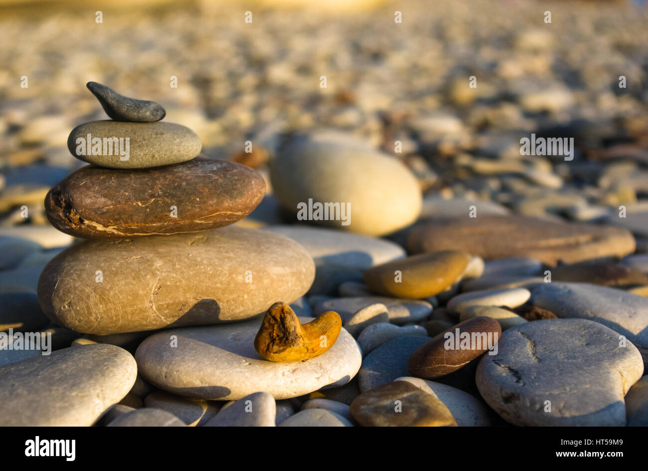 Piramide piegata Zen pietre ghiaia sul mare spiaggia al tramonto Foto Stock