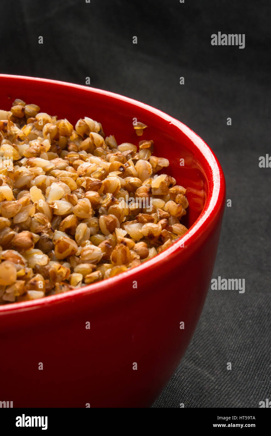 La dieta alimentare - Calda Cereali di grano saraceno in una ciotola di colore rosso su sfondo nero Foto Stock