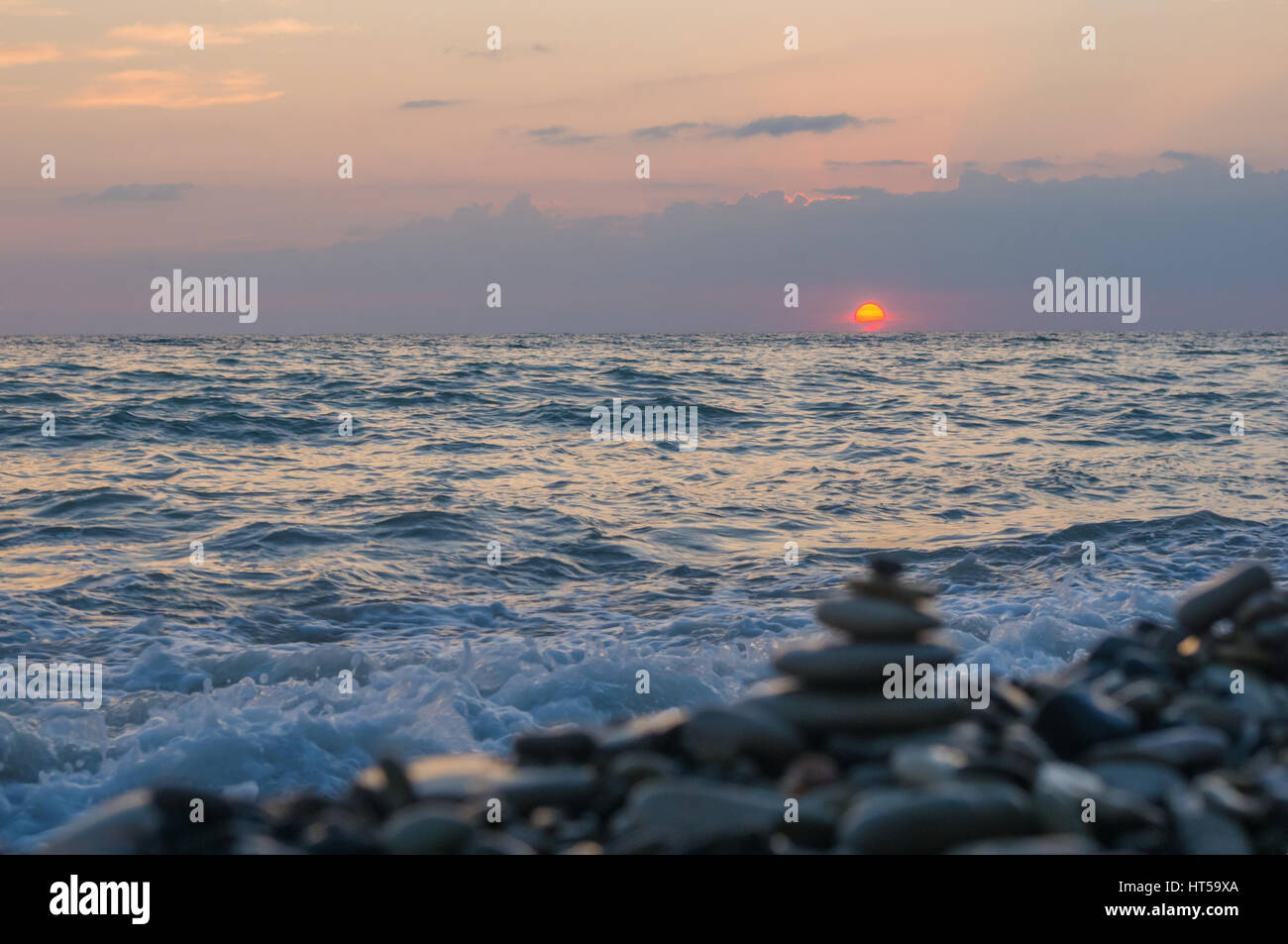 Piramide piegata Zen pietre ghiaia sul mare spiaggia al tramonto Foto Stock