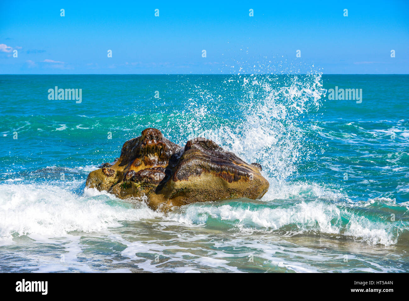 Grande onda crash contro le rocce in spiaggia. Foto Stock