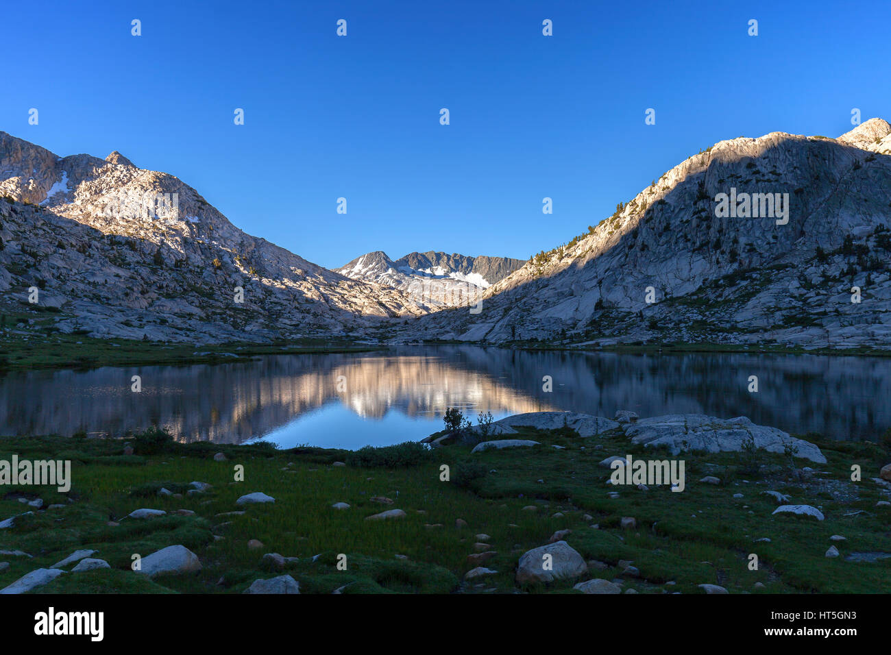 Primo sole del mattino si riversa attraverso il lago di evoluzione nella Sierra Nevada sulla Pacific Crest Trail. Foto Stock