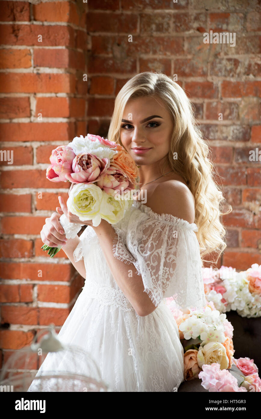 Sposa in posa sul muro di mattoni e vetro Foto Stock